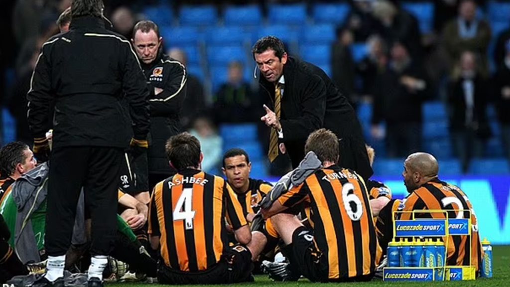 Phil Brown gives a team talk on the pitch for Hull vs City